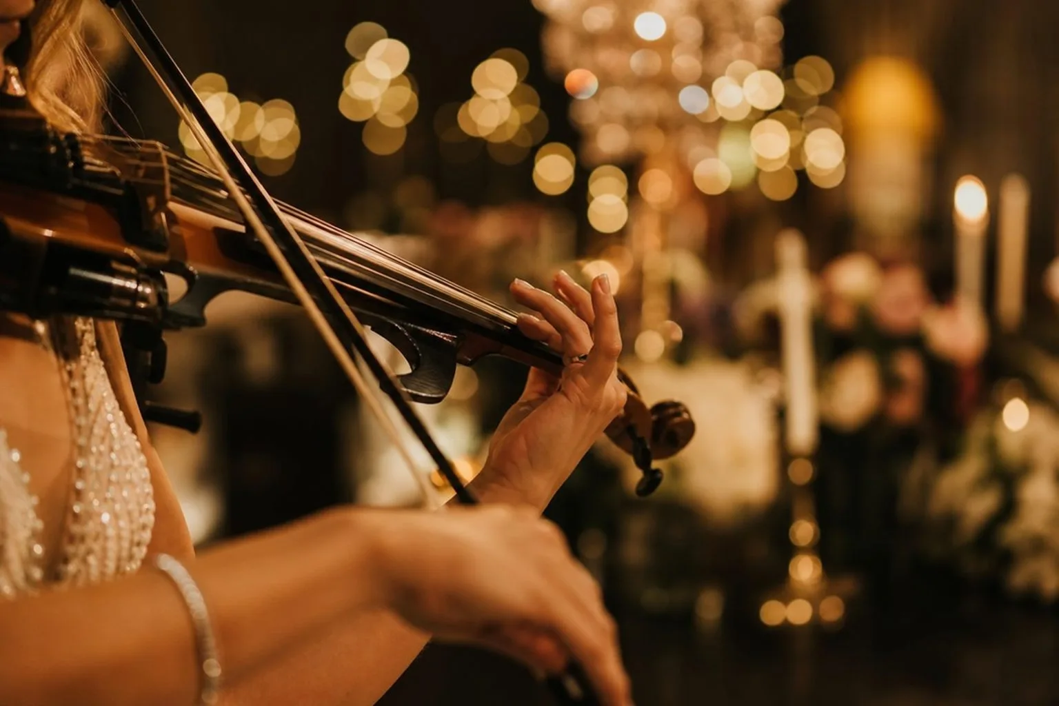 Violinistkinja svira na ceremoniji venčanja uz svetla u pozadini